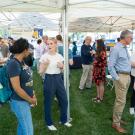 Wide shot of the exhibition tent, showing students presenting their research and mingling with alumni, faculty and staff, with the Graduate Alumni Network banner in the background.