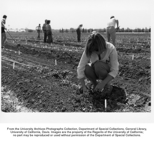 Person crouched over a field with other class members.