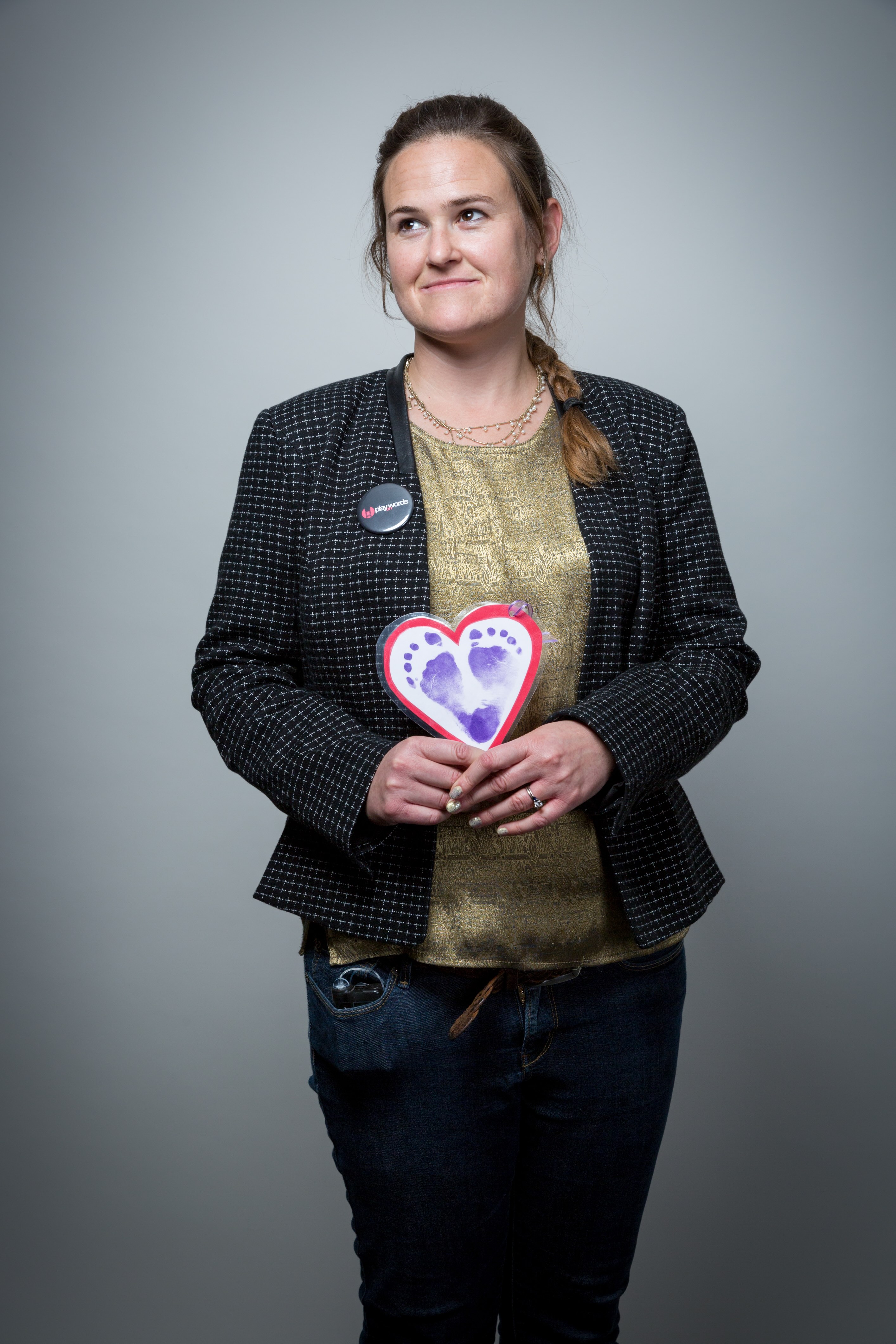 Julia Halprin Jackson smiling and and looking to the left while holding a paper heart with her child's painted footprints.
