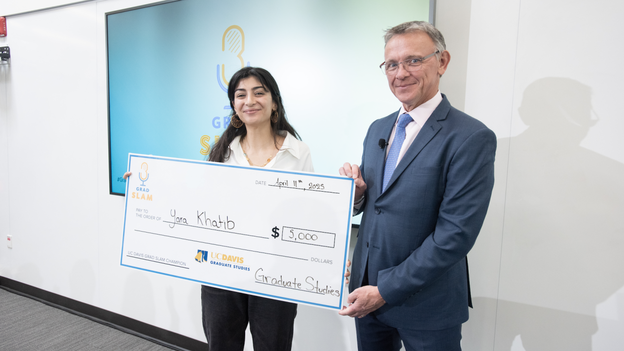 Yara Khatib smiling with giant check next to Dean Jean-Pierre Delplanque.