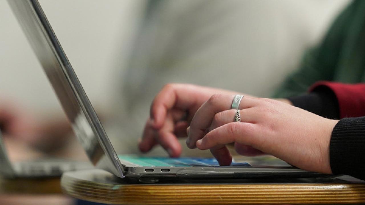 Hands with rings typing on a keyboard.