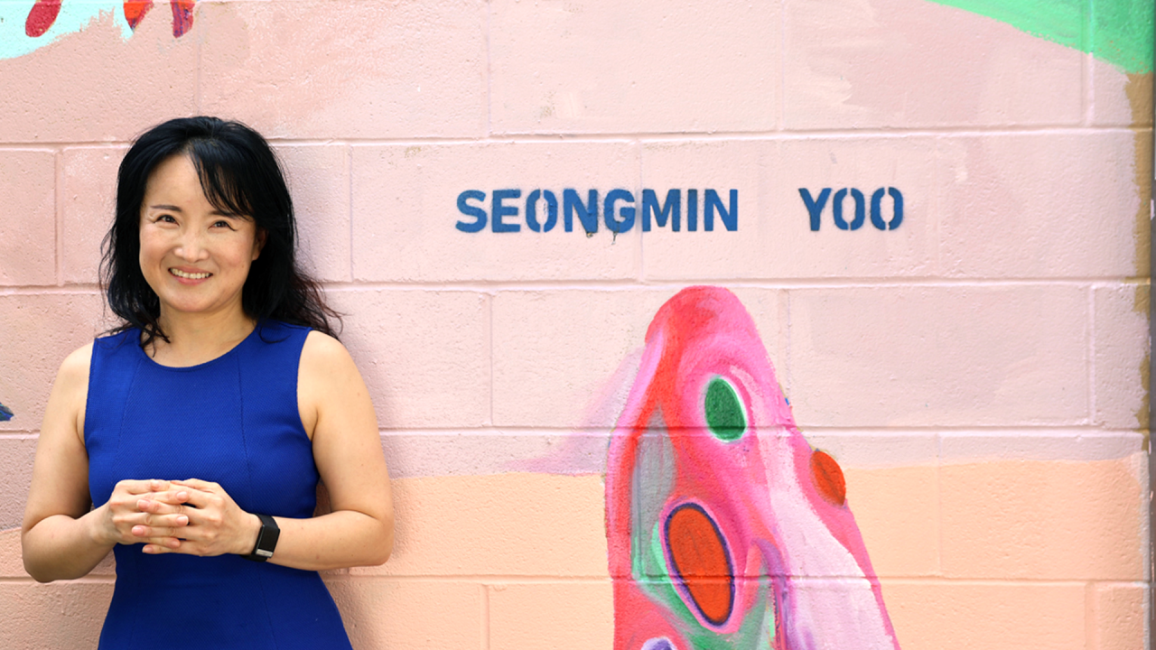 Artist Seongmin Yoo with a small section of her mural featuring aliens at Second and B Streets in downtown Davis. (Maria Sestito/UC Davis)