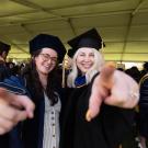 Student and professor pointing and smiling during the MFA and Doctoral Degree Ceremony at University Credit Union Center