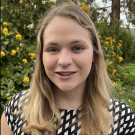 Lauren Hitt is wearing black top with white dots and standing in a garden