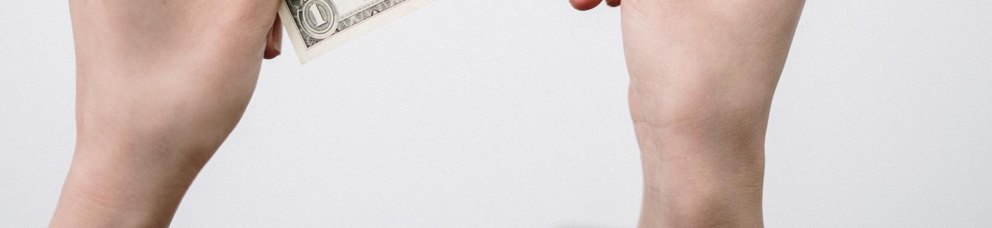 Set of hands holding a one dollar bill